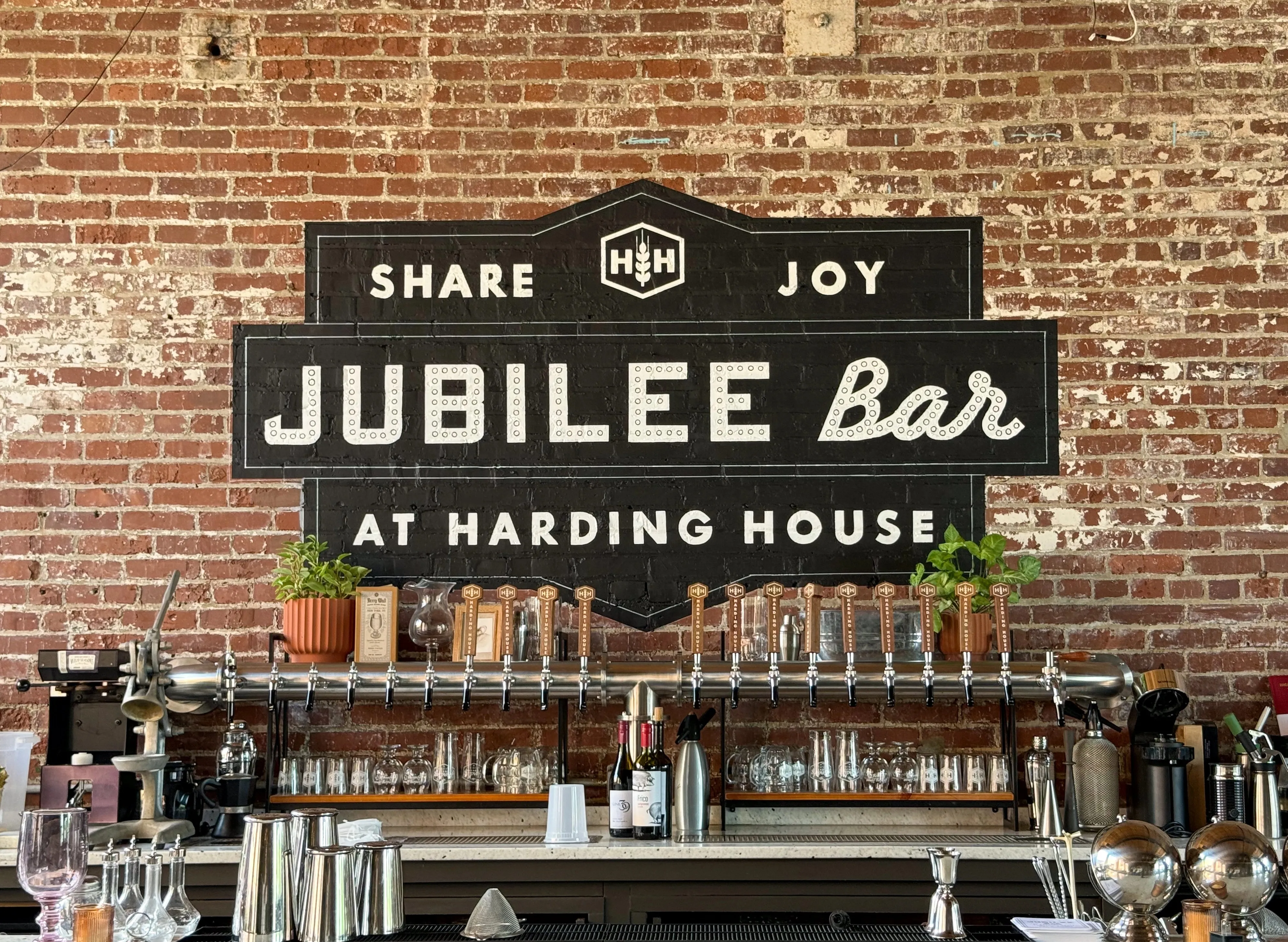 The Jubilee Bar at Harding House sign painted on the brick wall above the taps and back bar.