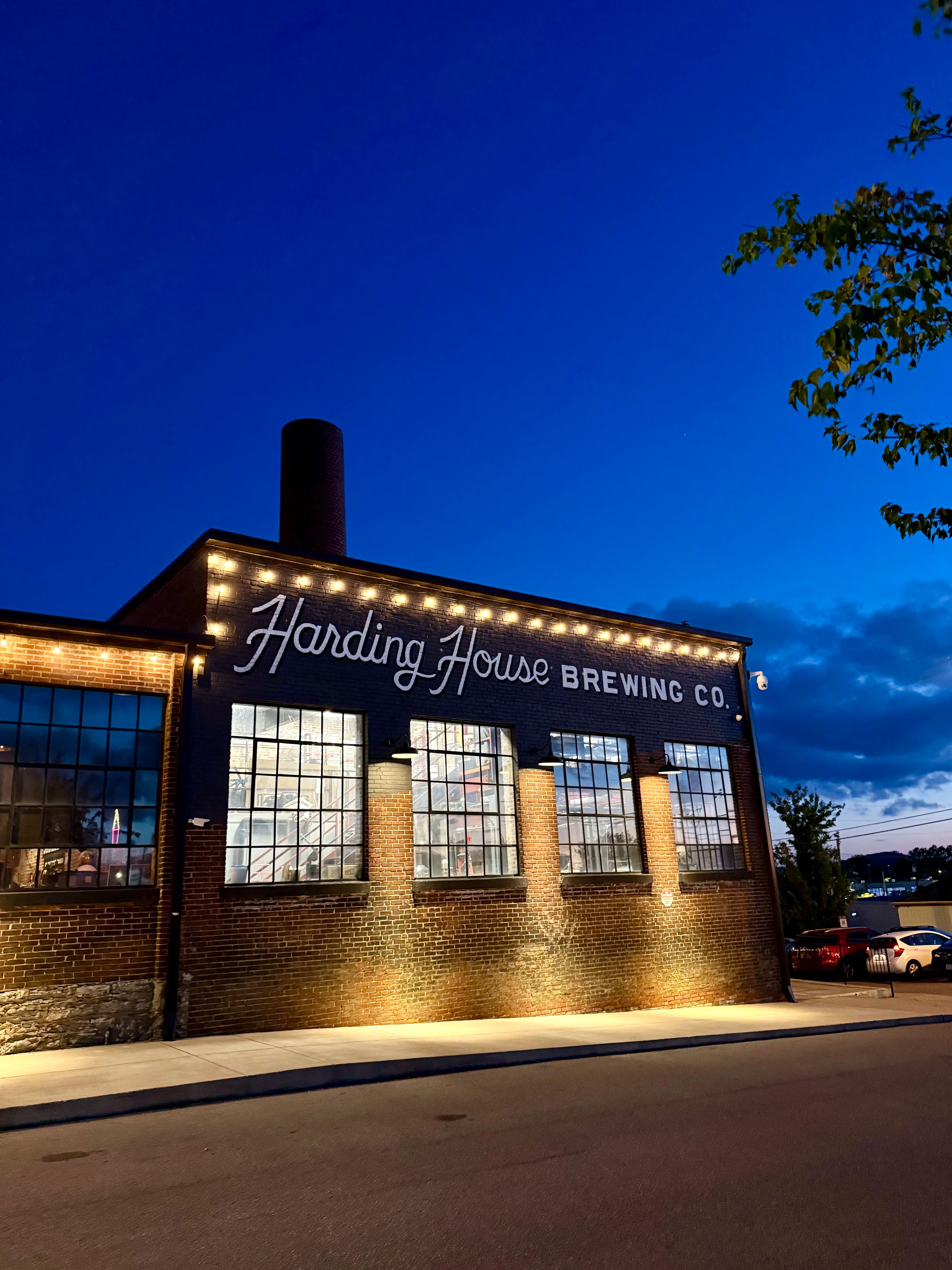 The Harding House Brewing Co. building at dusk, lit up with string lights.